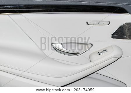 Door handle with Power seat and window contol buttons of a luxury passenger car. White leather interior of the luxury modern car. Modern car interior details