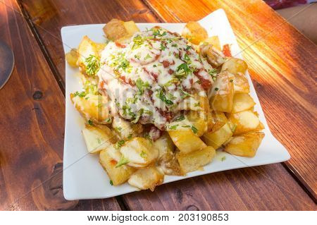 Spanish potatoes patatas bravas for tapas with tomato and white sauce with parsley. Selective focus
