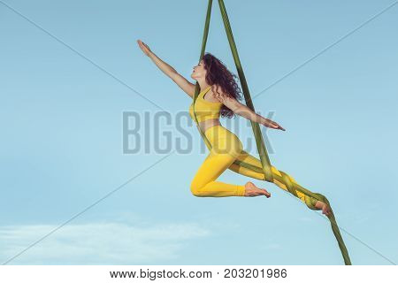 Female athlete by aerial acrobatics she makes a performance high in the sky.