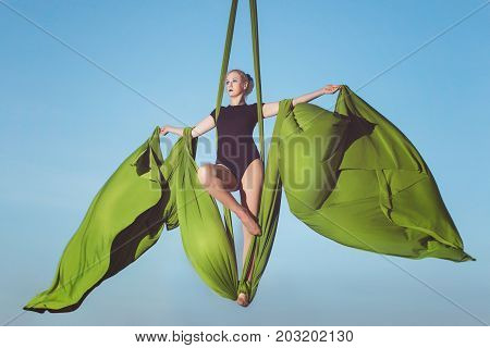 Woman flies on canvases high in the sky she is an acrobat.