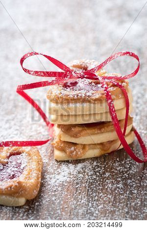 A pile of heart cookies on a rustic wooden table. You can use it for a greeting card or recipe.