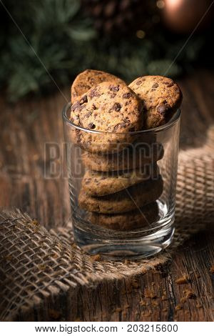 Fresh baked chocolate chip cookies in a glass on a rustic wooden table.