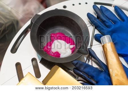 Hairdresser tools for hairdye top view. Hair dye in bowl, gloves for hair coloring
