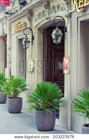 Paris, France - June 4, 2017: Side view of entrance four stars hotel Relais Saint Jacques surrounded by big gray outdoor planters with small palm trees. Vertical shot