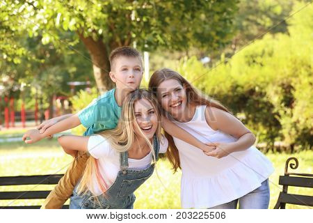 Lesbian mothers with foster son having fun in park