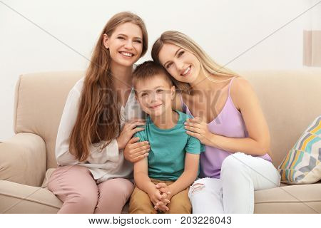 Happy lesbian couple with foster son at home. Adoption concept