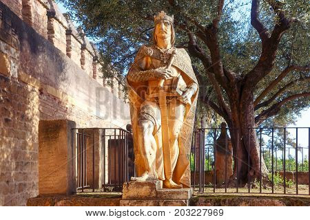 Stone statue of a medieval knight king in Alcazar de los Reyes Cristianos or Castle of the Christian Monarchs in the sunny day, Cordoba, Andalusia, Spain