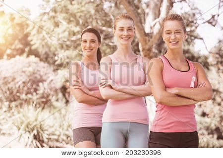 Portrait of confident female volunteers supporting breast cancer social issue at park
