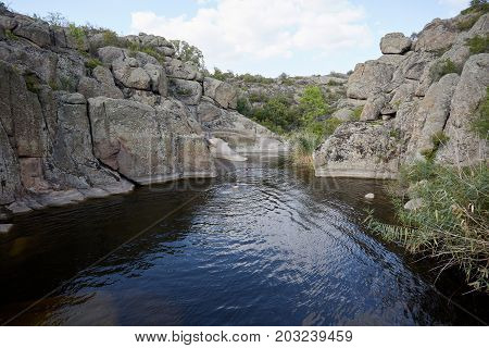 A couple of men swimming in increadibly beautiful lake in abandoned granite quarry on a blue sky background. Two swimmers in the wild nature. Summer, travel, rest, water concept. Copy space.