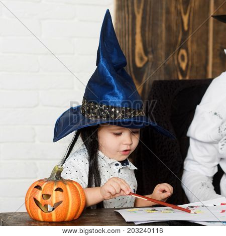 Man And Kid With Serious Faces In Witch Hats Draw