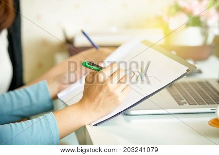 Women hands close up during wirting on graph paper.