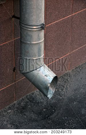 vertical metal tinplate drain pipe with bell at wall on street