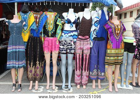 Brightly colored clothes on mannequins at a flea market