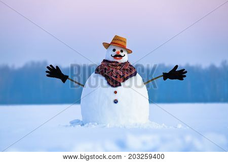 On the white fluffy textured snow alone snowman the friend is standing in nice hat and scarf with red nose. Beautiful winter background.