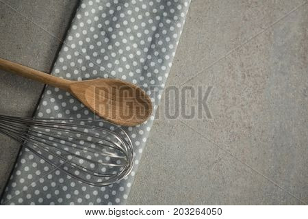 High anlge view of wooden spoon with wire whisk on napkin at table