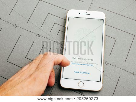 PARIS FRANCE - SEP 26 2016: Male hand holding New Apple iPhone 7 Plus after unboxing and testing by installing the app application software WhatsApp agreement prior use