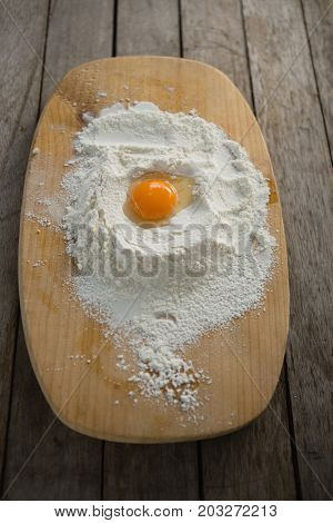 High anlge view of egg yolk in flour on cutting board at wooden table