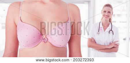 Mid section of woman wearing pink bra for breast cancer social issue against confident female doctor smiling at camera