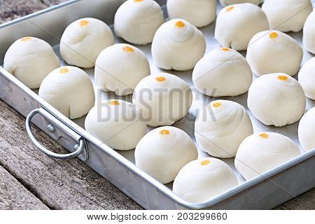 Dessert Chinese pastry : The dough for homemade pastry making with salted egg yolk and a scented candle in baking tray on wooden desk background. For Chinese new year or mooncake.