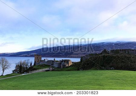 Panoramic view of Urquhart Castle and fortress with Scottish Flag waving on a winter's day with snow capped mountains and Loch Ness in the background.
