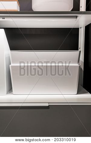 Closed up white storage on shelf and drawer in walkin closet against grey wall.