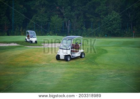 two golf cars on a green golf course