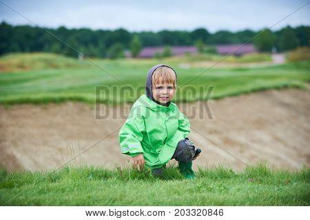 little boy walking the green golf course