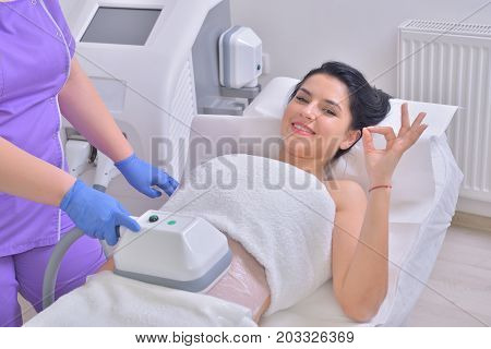 Beautiful young woman getting cryolipolyse fat treatment in professional cosmetic cabinet