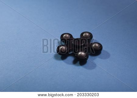 Fidget spinner on a blue background, trendy anti-stress gadget