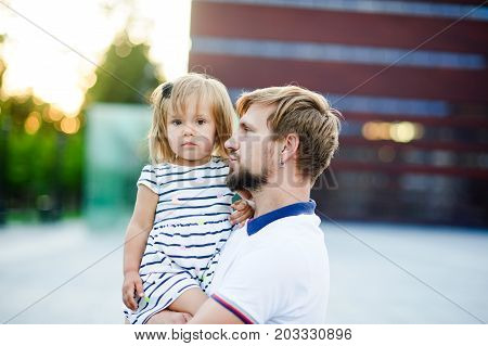 Young father holds the little daughter on hands. Man gently presses to himself the child.