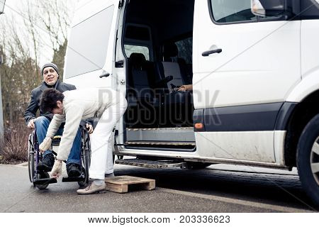 nurse helping senior man exit a van and get to his wheelchair