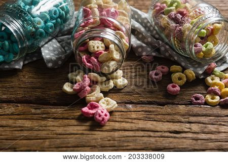 Close-up of scattered honeycomb cereals from jar on wooden table