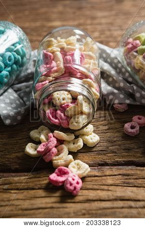 Close-up of scattered honeycomb cereals from jar on wooden table