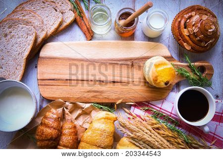 Fresh tasty bread with coffee and honey bee with milk on the table.