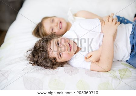 A Brother And Sister Relaxing Together In Bed