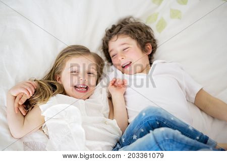 A Brother And Sister Relaxing Together In Bed