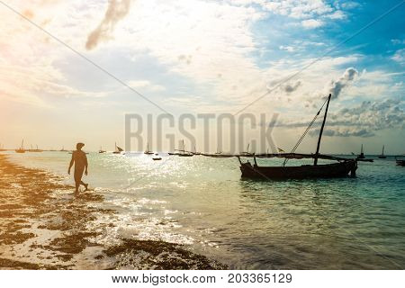 Lone primitive boat with masts in shallow waters of the ocean, sunny day, local people