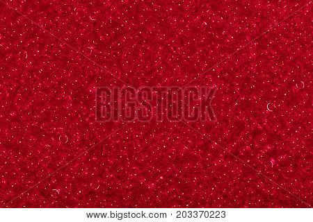 Seed beads of red color on the textile background close up