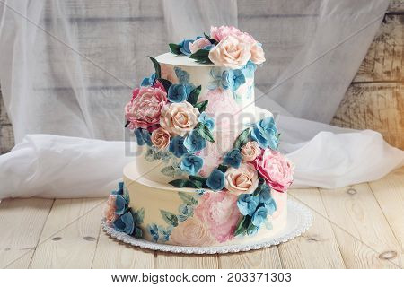 A Beautiful Home Wedding Three-tiered Cake Decorated With Pink Roses And Blue Flowers In A Rustic St
