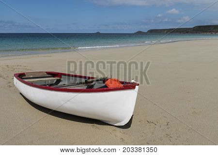 White small boat on beach at Sennen Cove in summer Cornwall England.