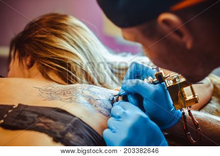 tattooer showing process of making a tattoo hands holding a tatoo machine