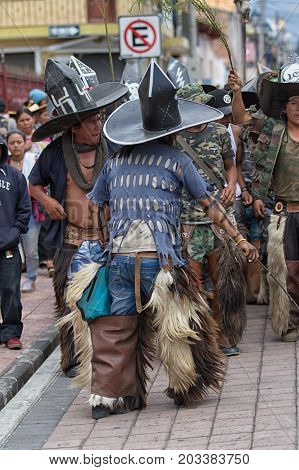 June 29 2017 Cotacachi Ecuador: kichwa indigenous people with extra large hats and chaps dancing on the street during Inti Raymi festival