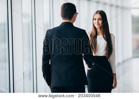 Businessman And Businesswoman Shaking Hands In Office With Big Panoramic Windows In Office