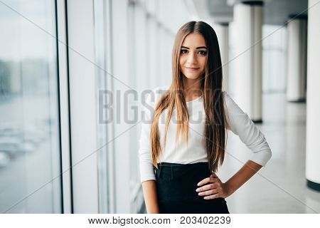 Young White Businesswoman Leaning At Window At Work