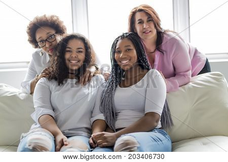 Two family Friends Sitting On Sofa Together having fun