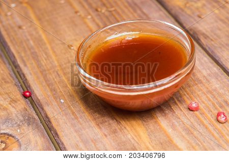 Sauce in a glass bowl on a background of a board