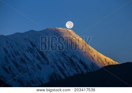 Beautiful landscape in Himalayas Annapurna region Nepal. Full moon during a sunrise on the background of snow-capped mountains