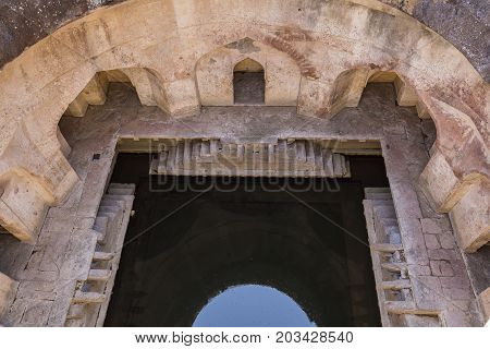 Arched architecture and a well with water in the palace Jahaz Mahal . Mandu Madhya Pradesh India