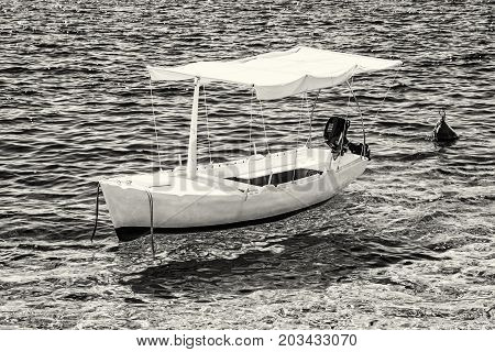 Anchored little boat in Maslinica Solta island Croatia. Summer vacation destination. Black and white photo.