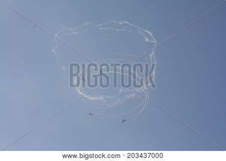 Beautiful acrobatics show of a group of gliders in a sunny sky. Draw colorful loops in the sky.